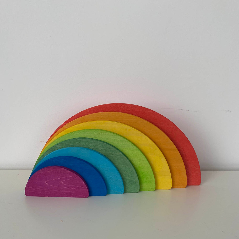 A wooden semicircle stacker toy with rainbow colors displayed on a white background.