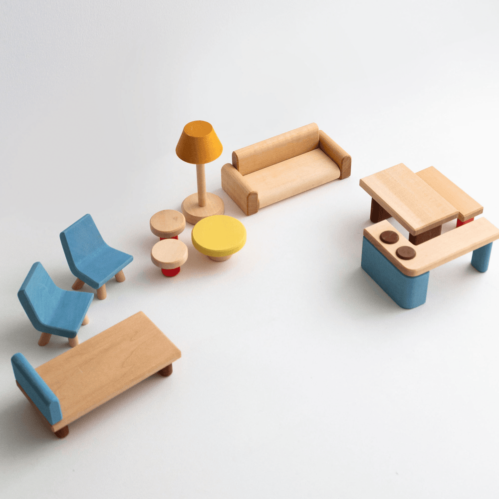 A collection of wooden dollhouse furniture including a bed, table, kitchen counter, sofa, two chairs, stools, and a bench, with a natural wood finish and some painted details.