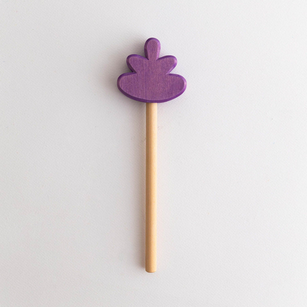 A wooden flower wand with a purple petal-shaped top on a light background.