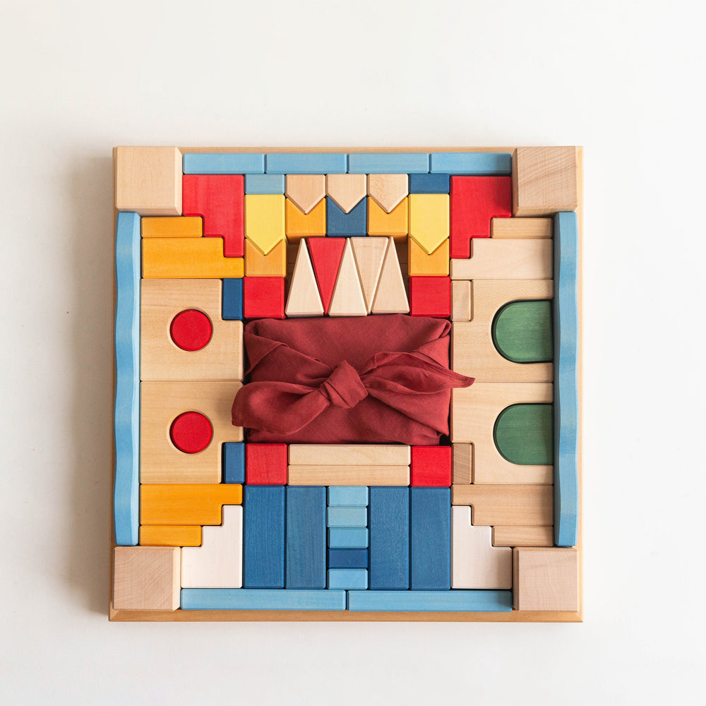Colorful wooden block puzzle with a red fabric bow on a white background