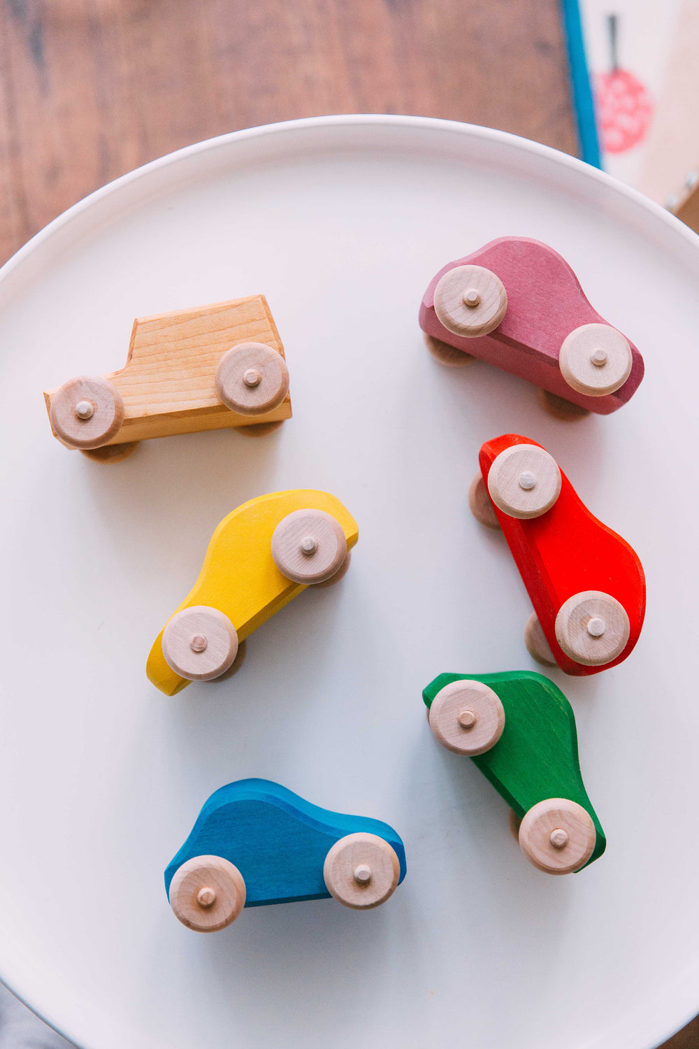 Six wooden cars in pink, red, green, blue, yellow and beige
