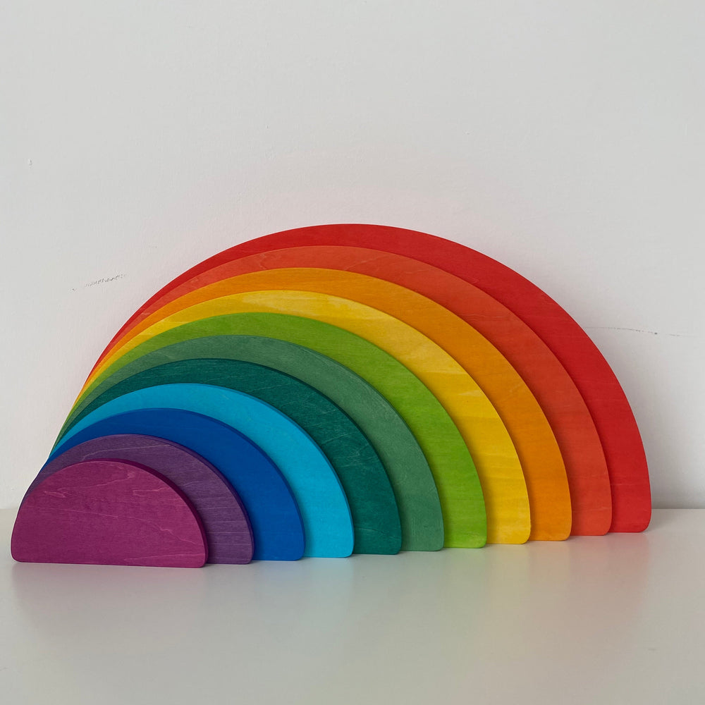 A wooden semicircle stacker toy with rainbow colors displayed on a white background.