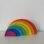 A wooden semicircle stacker toy with rainbow colors displayed on a white background.