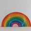 A colorful wooden rainbow stacker toy with multiple arches in various sizes arranged in a spiral pattern on a white background.