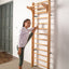 A woman leans on a wooden wall bar set with multiple rungs, mounted on a white wall
