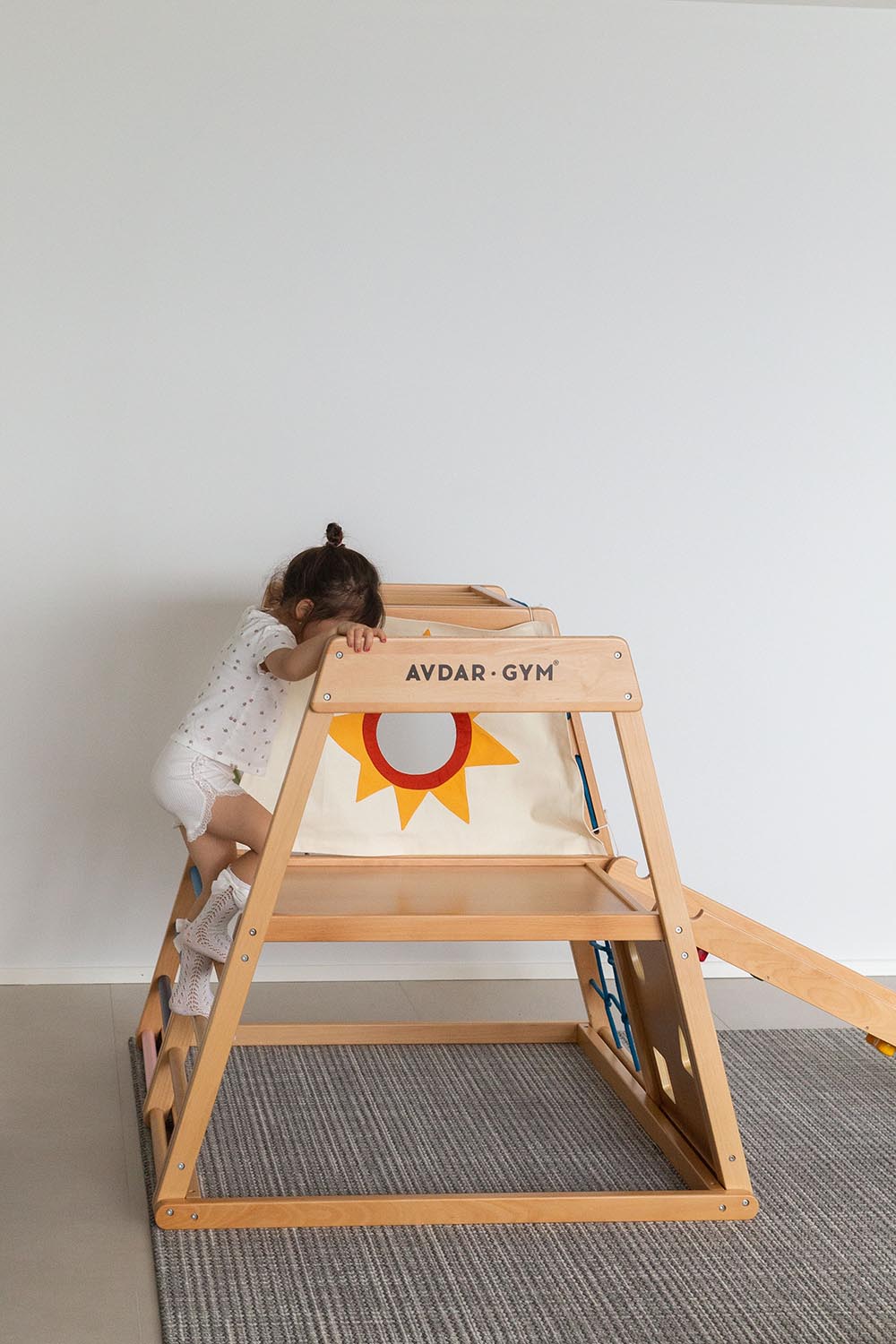 A child playing on a wooden climbing frame from the wooden ladder