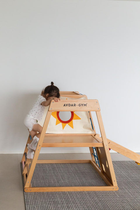 A child playing on a wooden climbing frame from the wooden ladder