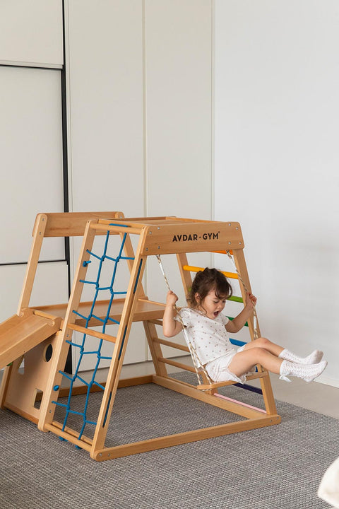 A child playing on the swing of the wooden climber