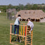 There are three kids playing on the wooden rainbow climber.  