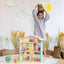 A girl play the wooden dollhouse with featuring two stories, an attic, and a balcony. 