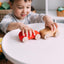 A boy plays two wooden cars on the white coffee table